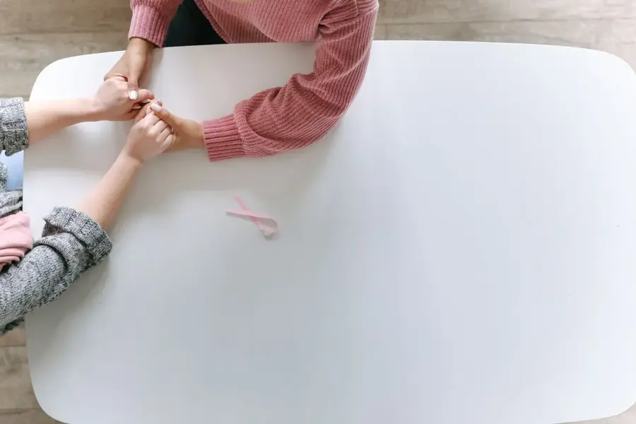 Des mains réunies et un ruban rose